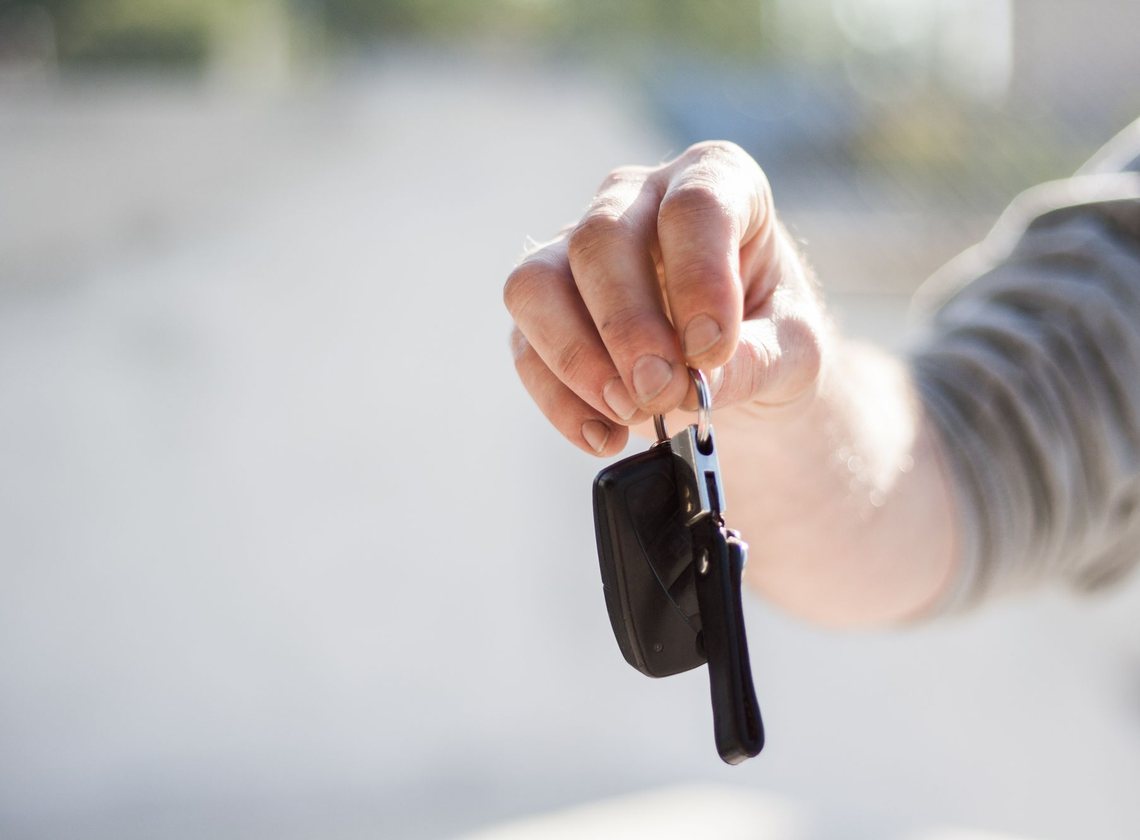 Mão estendida entregando uma chave de carro com controle remoto preto