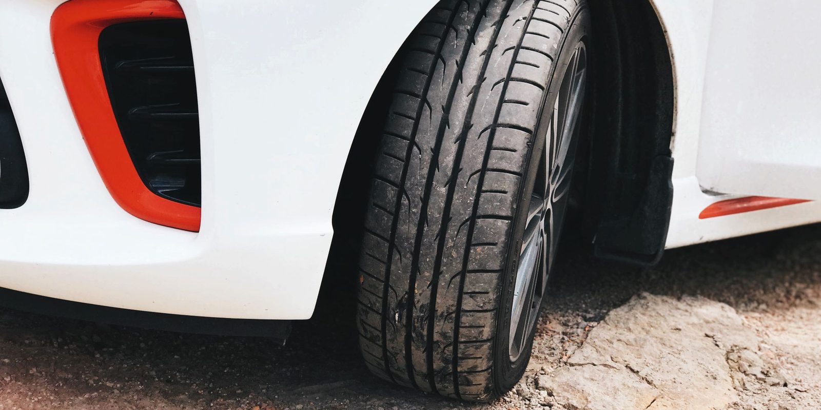 Pneu de um carro branco visto de perto, com os sulcos da banda de rodagem à mostra
